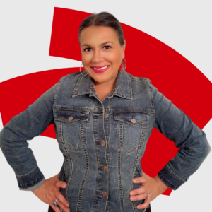 Smiling woman in a blue denim jacket, hands on hips, hoop earrings, red abstract shapes behind.