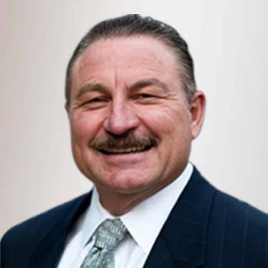 Smiling man in a dark suit and light tie, facing the camera.
