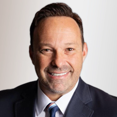 Professional headshot of a smiling man in a dark suit and tie, neutral background, ready for a business profile